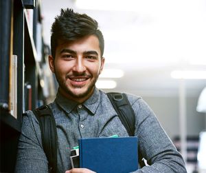 student in a library holding books